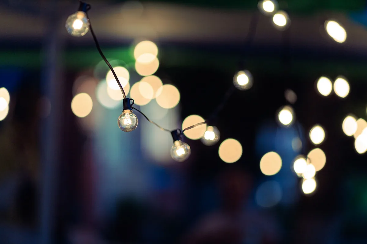 Cadena de bombillas encendidas de noche con luces desenfocadas al fondo