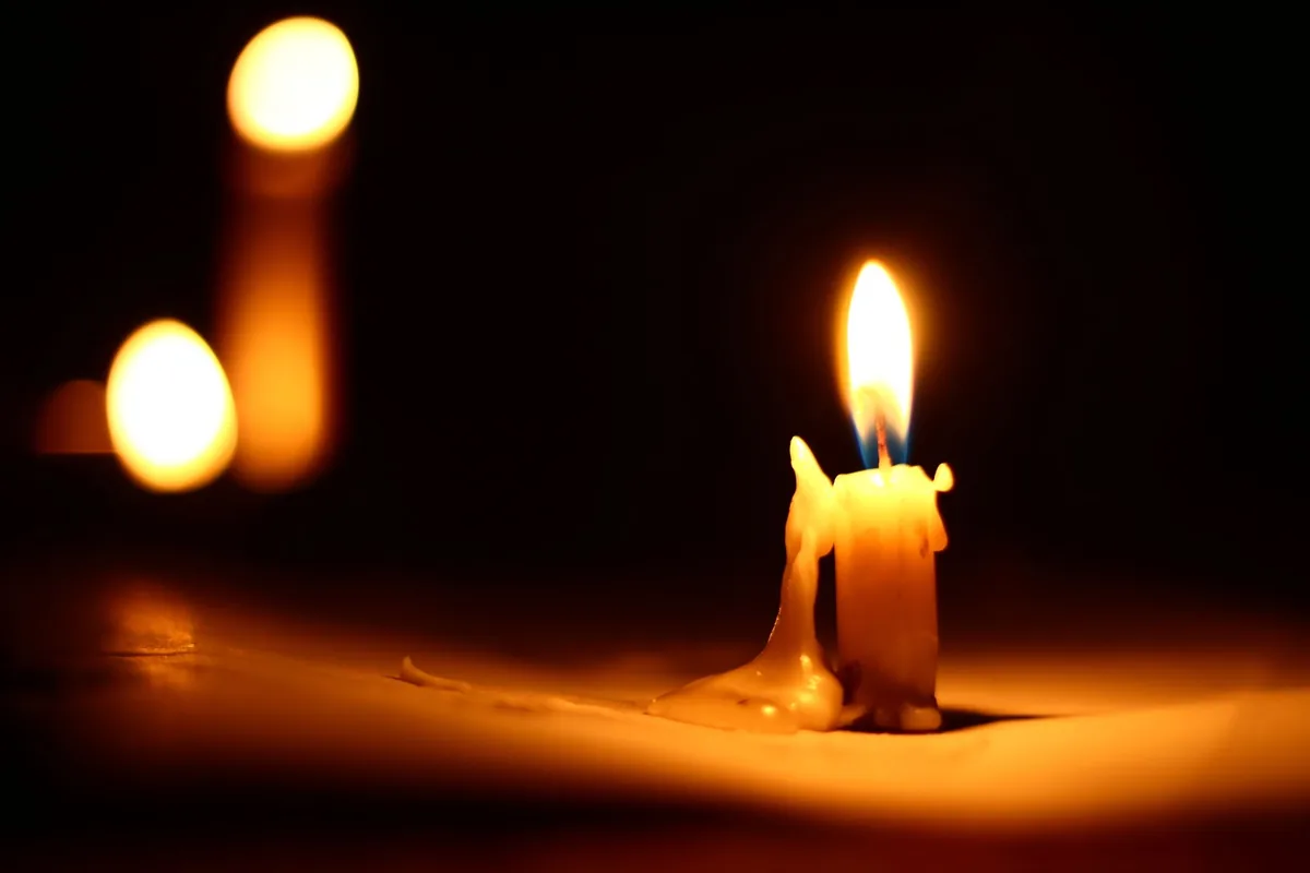 Una vela encendida con la cera derretida a un lado, en plena oscuridad