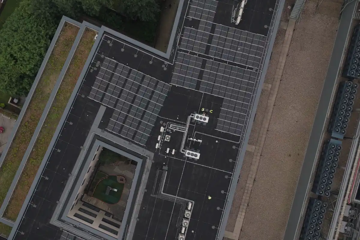 Vista aérea de una cubierta plana con filas de placas solares y equipos de climatización