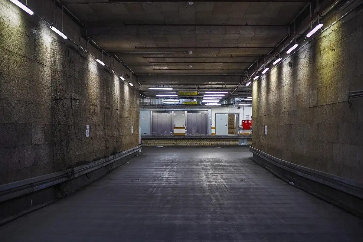 Rampa interior subterránea con tubos fluorescentes a lo largo de una pared de piedra