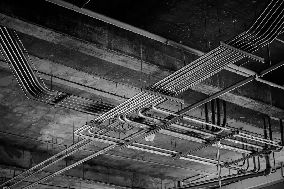 Tubos y bandejas metálicas con la instalación eléctrica recorriendo el techo de hormigón de un garaje