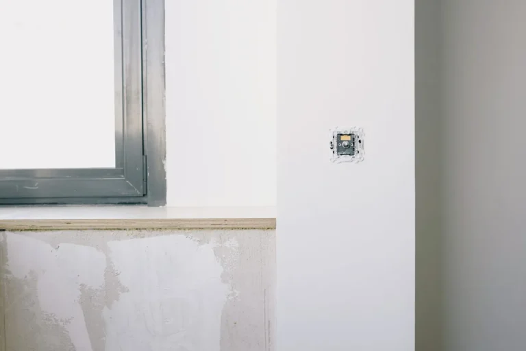 Mecanismo eléctrico recién empotrado en la pared de una vivienda en reforma, junto a la ventana