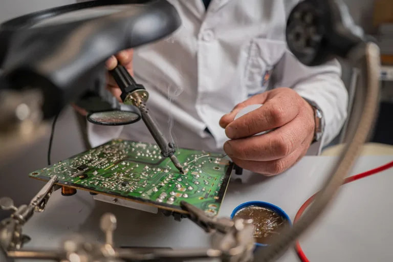 Técnico soldando la placa electrónica de un electrodoméstico con ayuda de una lupa